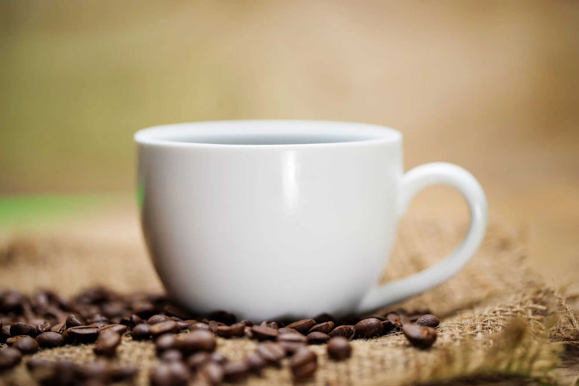 Freshly roasted whole coffee beans pouring across a dark surface