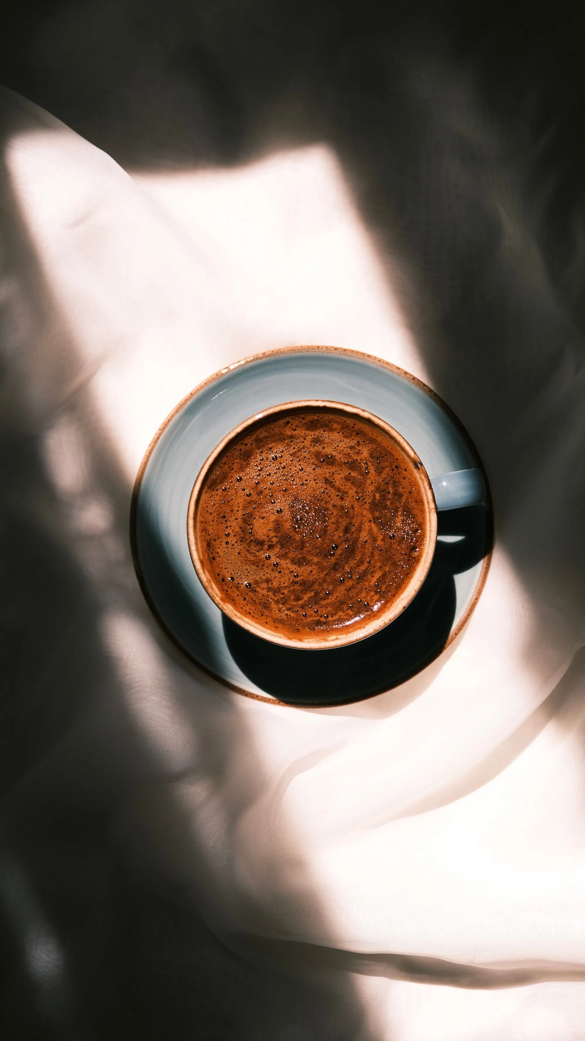 A single cup of black coffee on a dark surface