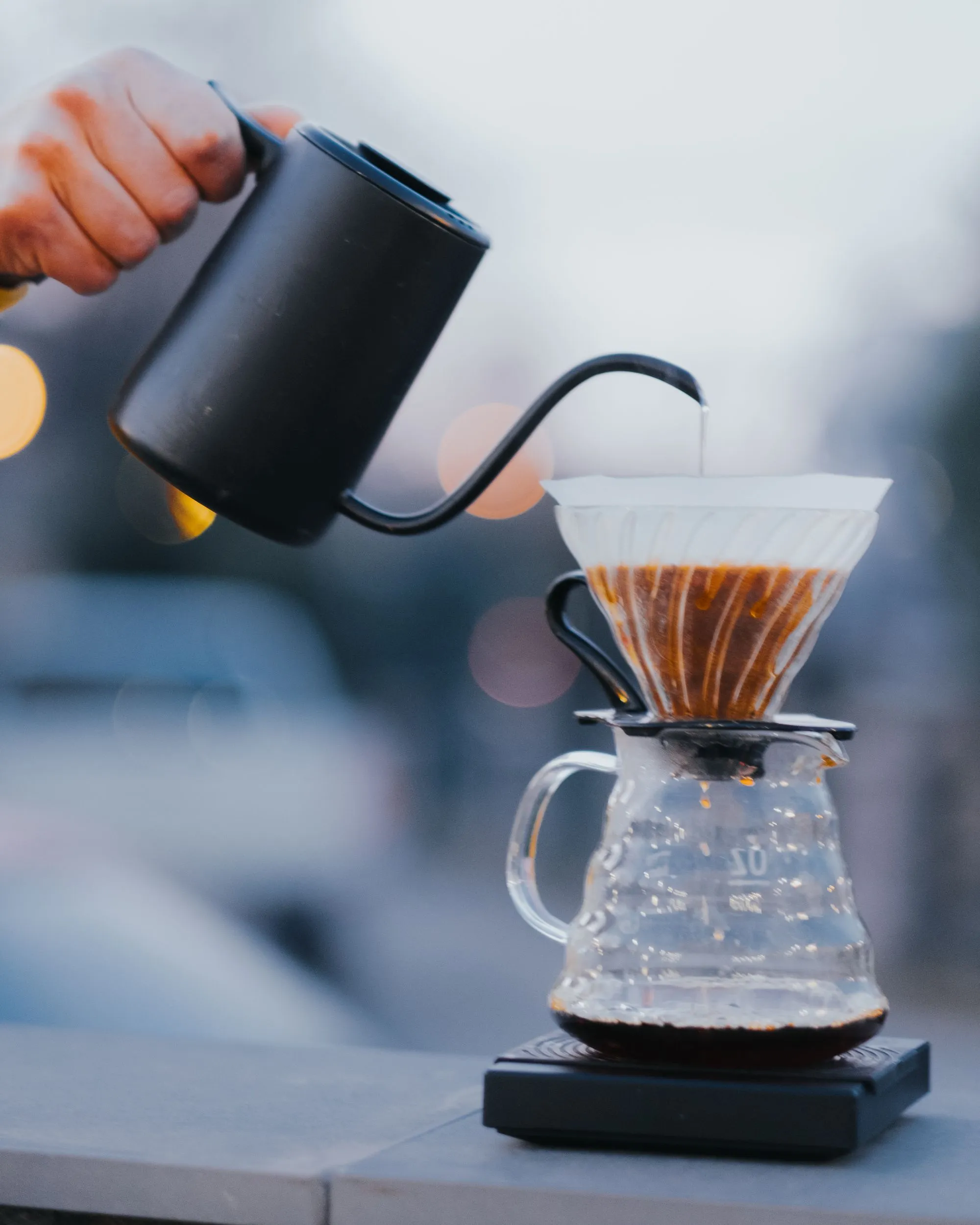 A slow, steady pour over a cone dripper blooming a fresh bed of coffee